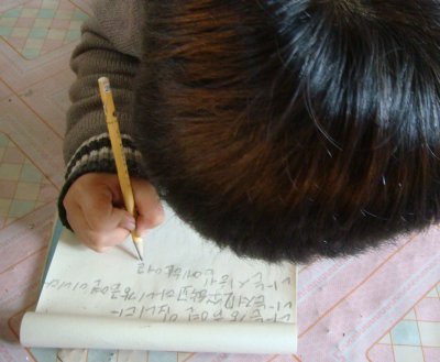 Refugee child in one of LFNKR's shelters writing to foster parent in Japan.